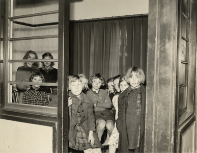 98448 Afbeelding van een aantal kinderen in een kamer van één van de, door de Stichting Volkswoningen beheerde stenen ...